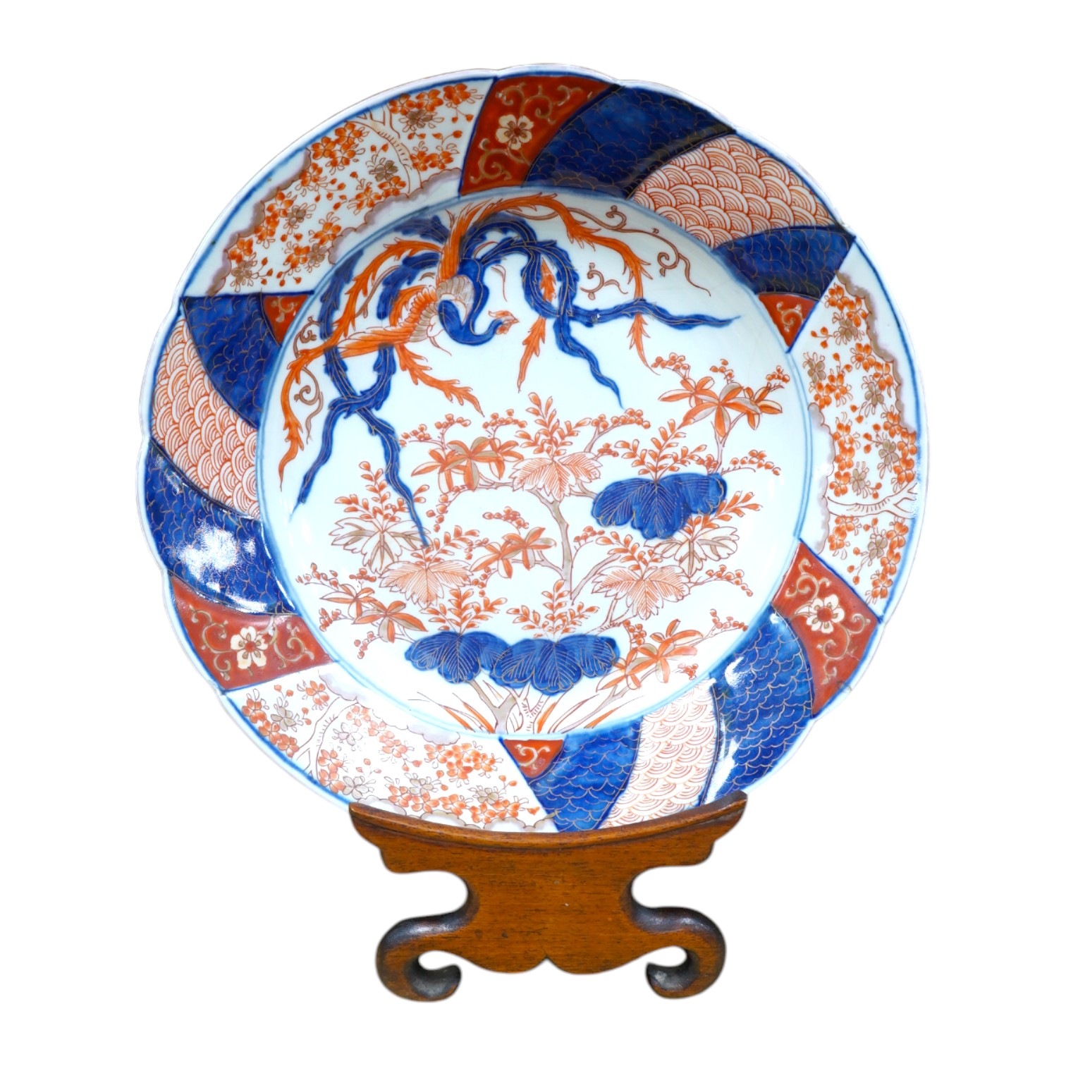 A Japanese Imari dish, circa 1900, on carved wooden stand, 31cm diameter. Condition - fine crack top right base of dish